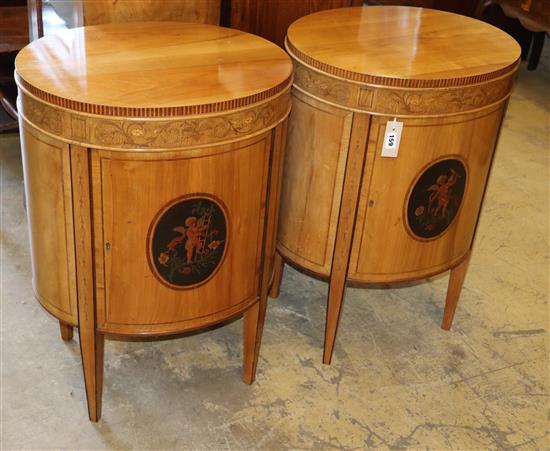 A pair of Edwardian inlaid satinwood bedside cupboards of oval form, decorated with cupid panels, W.51cm, H.73cm